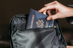 Persona poniendo pasaporte en una mochila.
