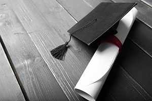 diploma y gorra de graduación en un piso de madera negra