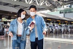pasajeros asiáticos con mascarilla caminando en la terminal del aeropuerto