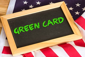 las palabras tarjeta verde escritas en una pequeña pizarra negra sobre una bandera estadounidense